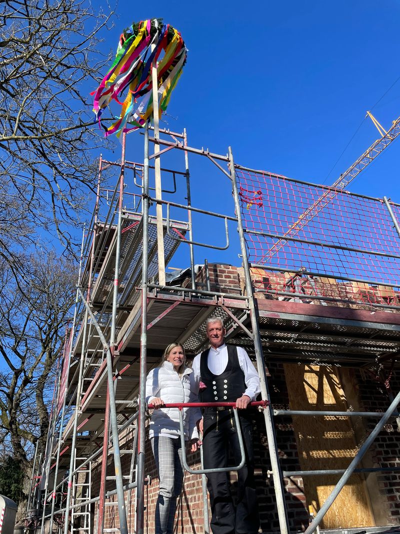 Bürgermeisterin steht neben Zimmermann auf dem Baugerüst.